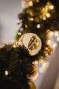 Christmas golden bauble on artificial fir garland full of lights on blurred background