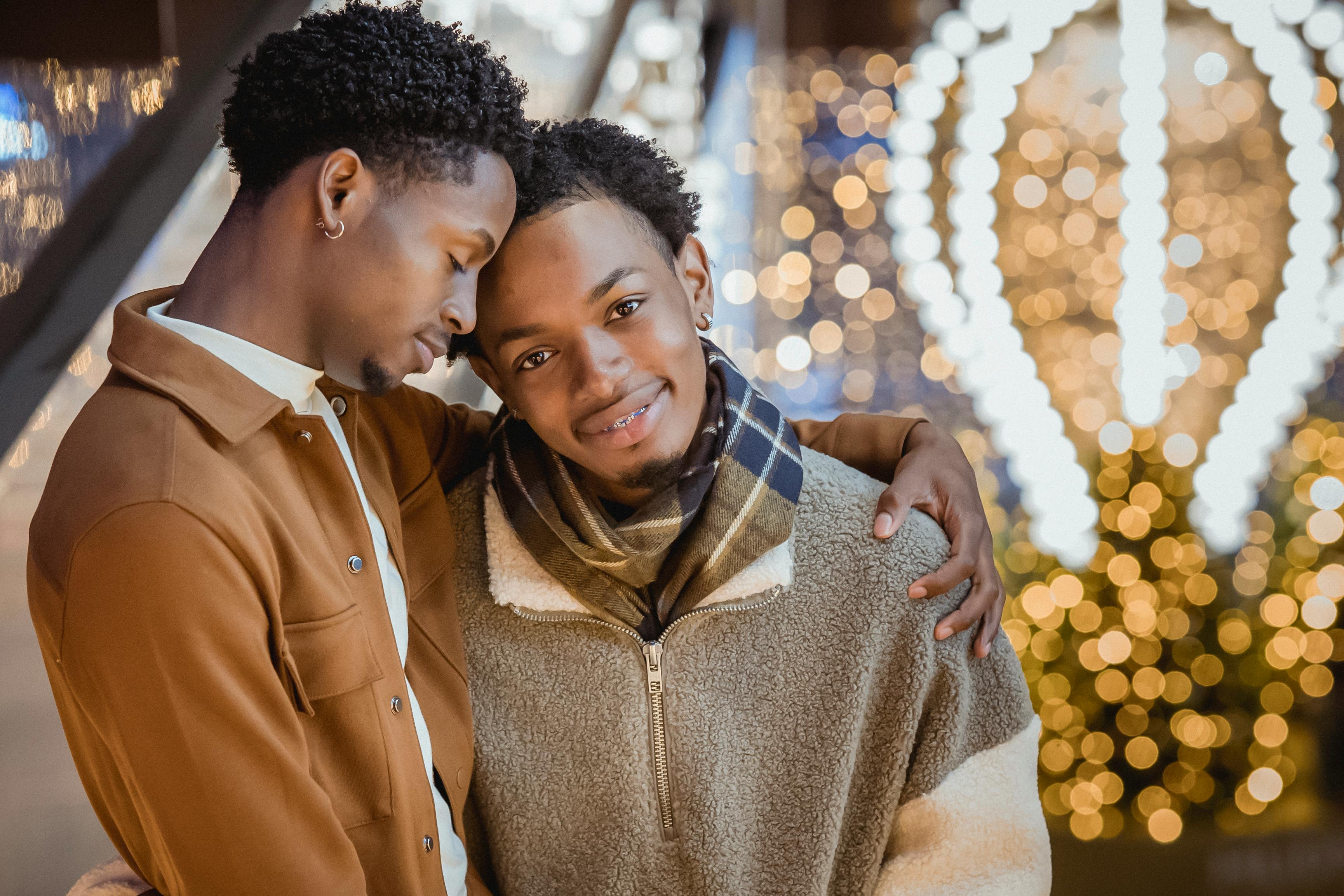 young black man looking at camera while hugging partner