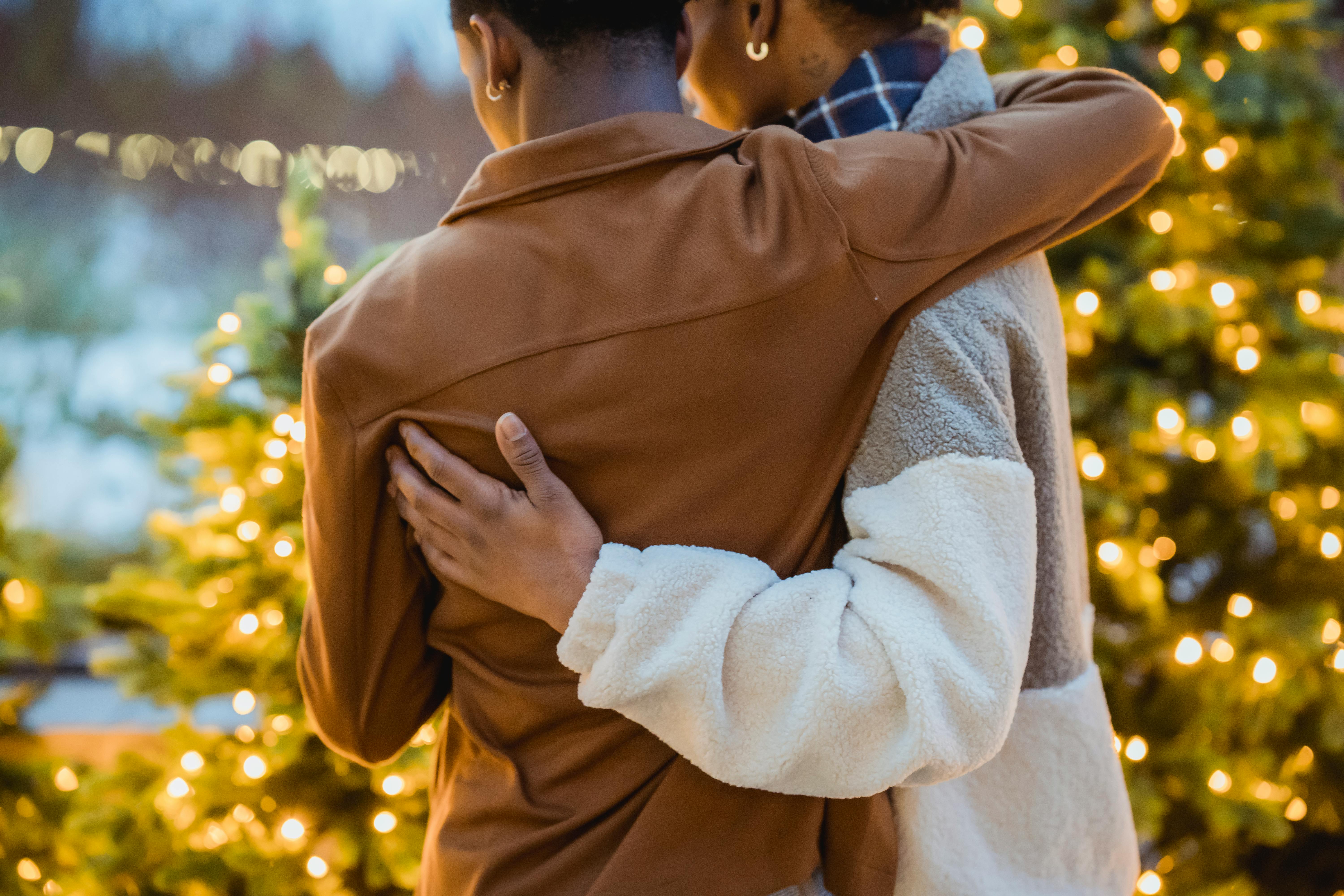 faceless african american homosexual couple hugging near decorated christmas trees