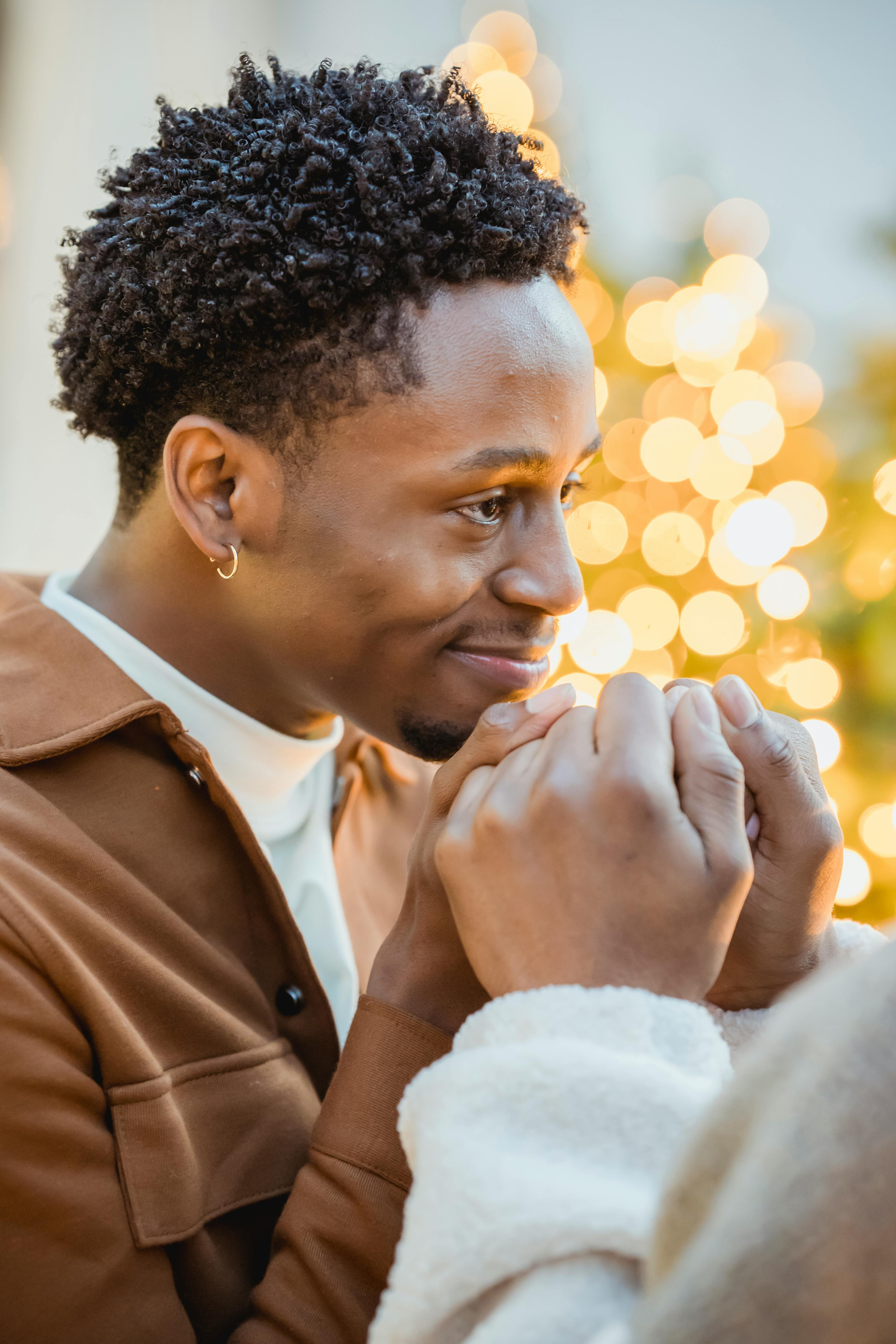 african american homosexual couple holding hands near garlands in street