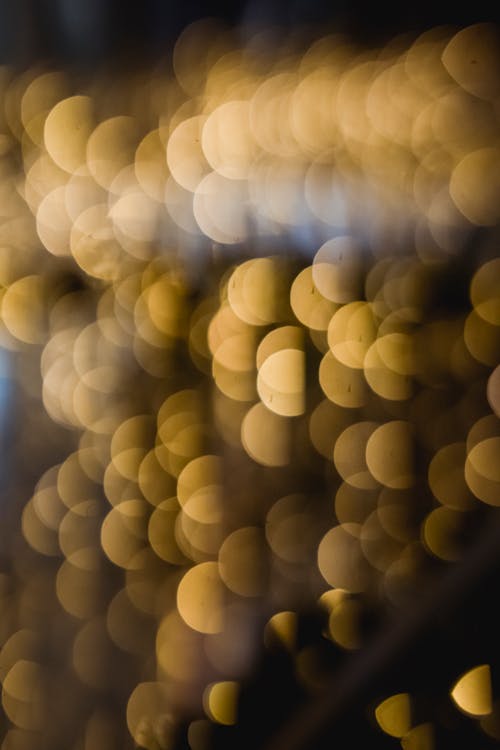 Many defocused shiny round yellow lights of garlands glowing on background in dark place