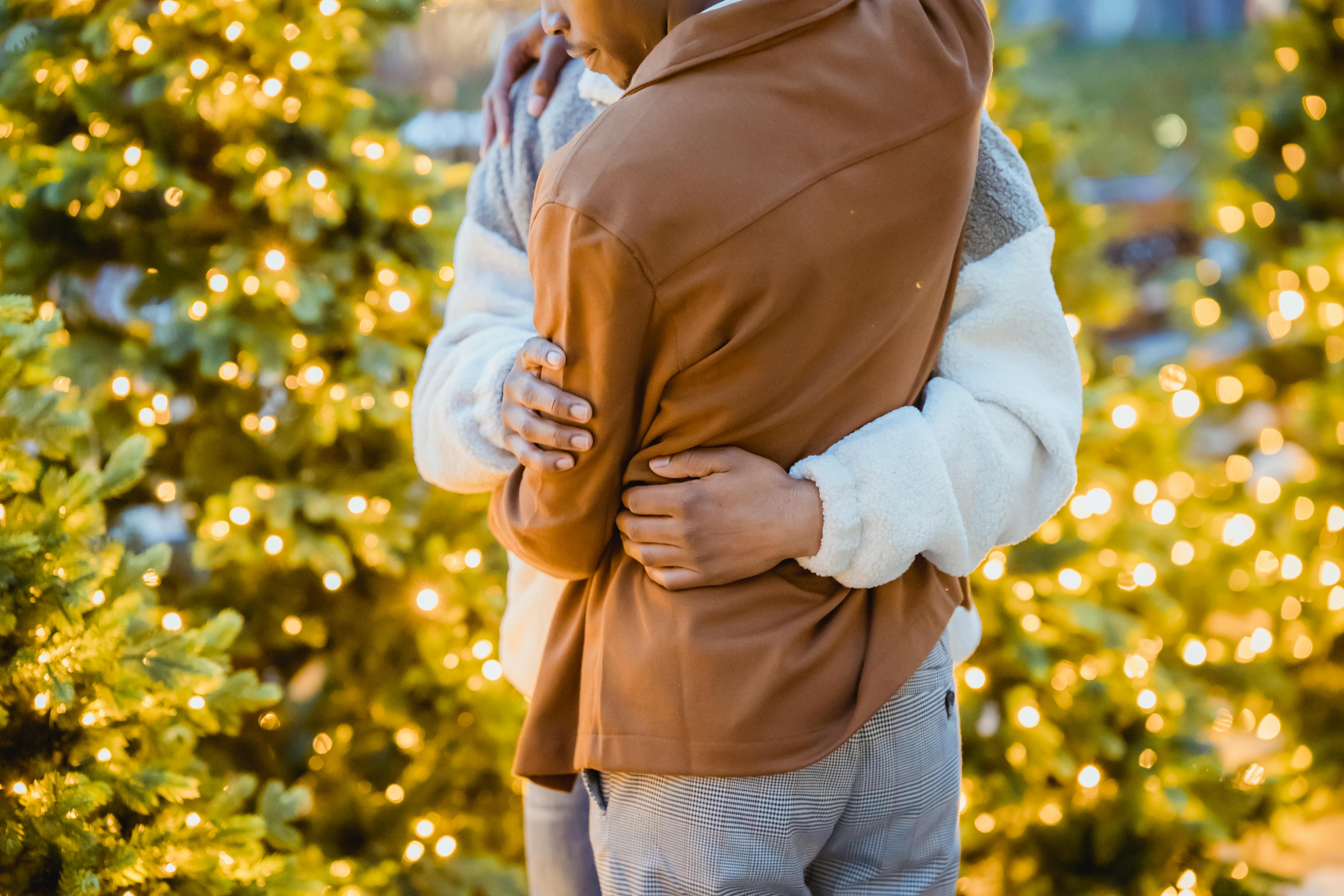 unrecognizable african american homosexual couple embracing near decorated christmas trees