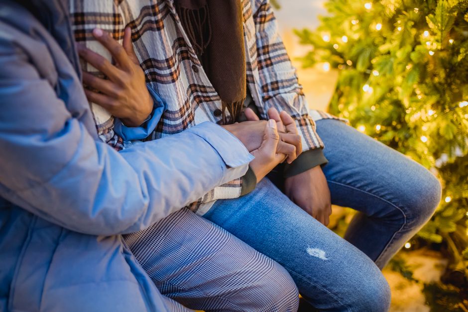 クリスマスツリーの煌めくライトの近くでカップルが抱き合っている温かい瞬間が捉えられました。