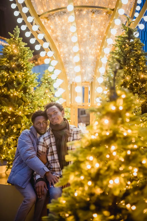 Tender black gays near illuminated Christmas trees