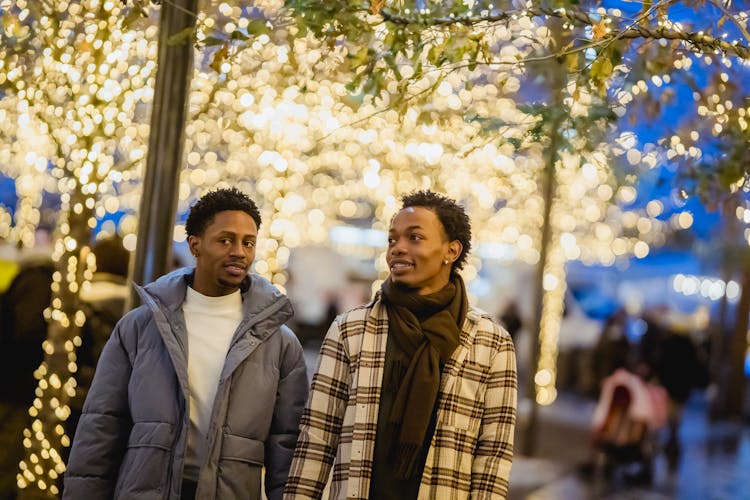 Content Black Homosexual Couple Walking On Street With Glowing Lights