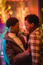 Flirting black gays near building with glowing lights