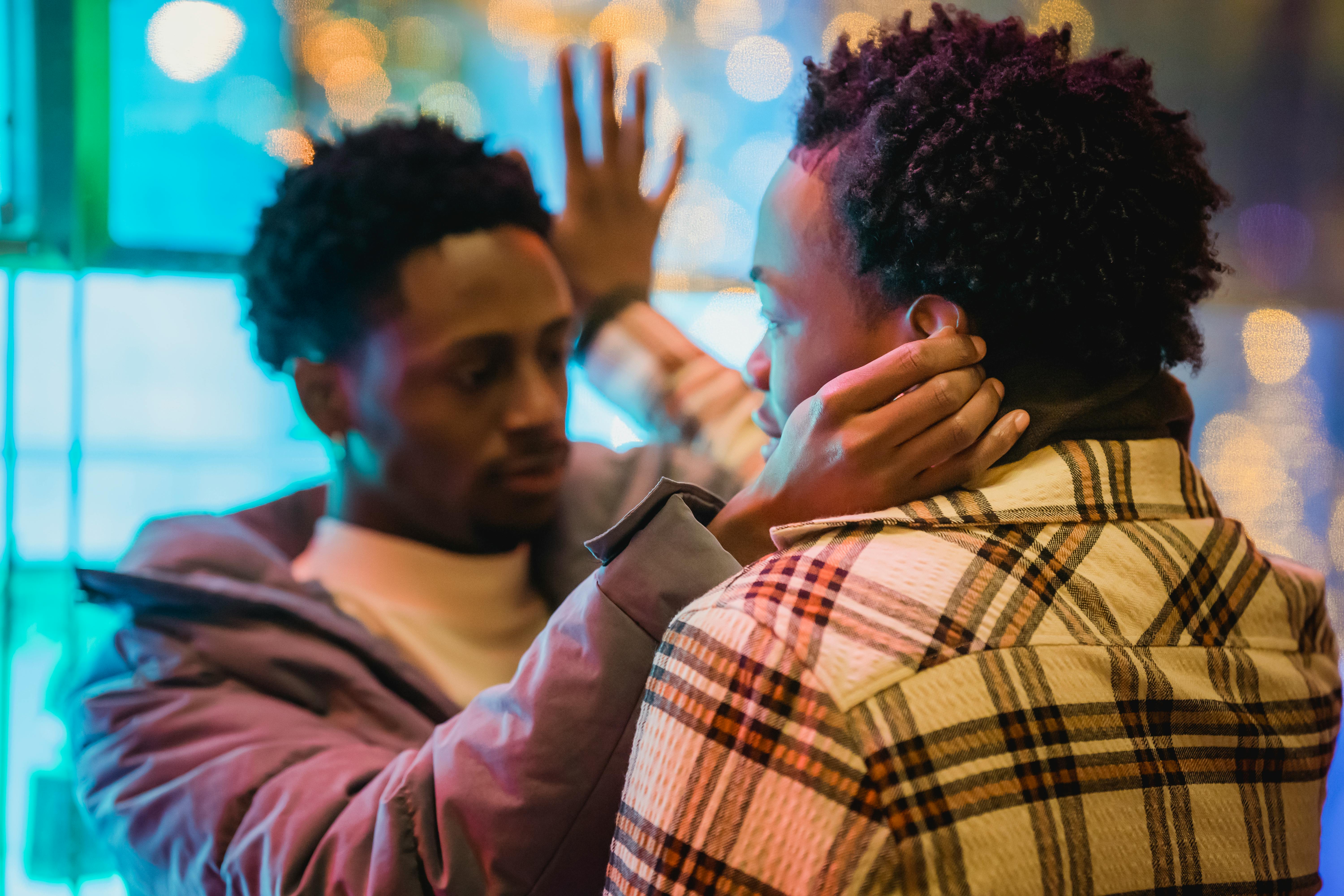 black gay touching ears of boyfriend in checkered shirt