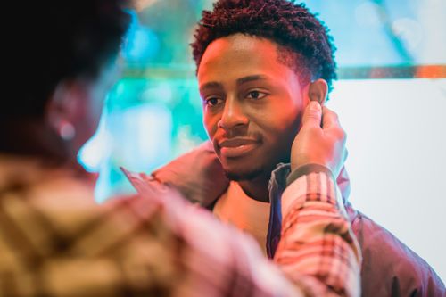 Free Crop anonymous African American male touching ears of smiling gentle boyfriend on glowing street Stock Photo