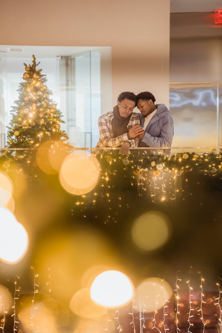 Couple Of Black Homosexual Men Holding Hands Among Christmas Decorations