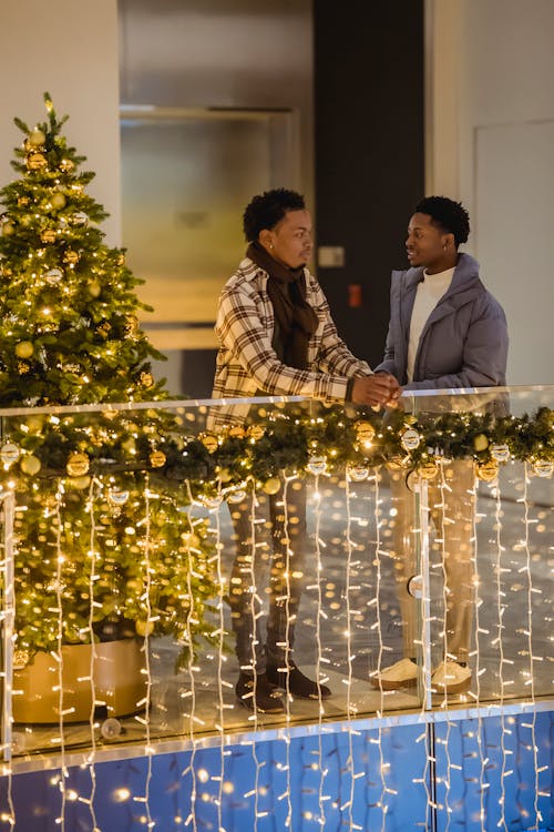 Black friends talking among luminous garland and Christmas tree