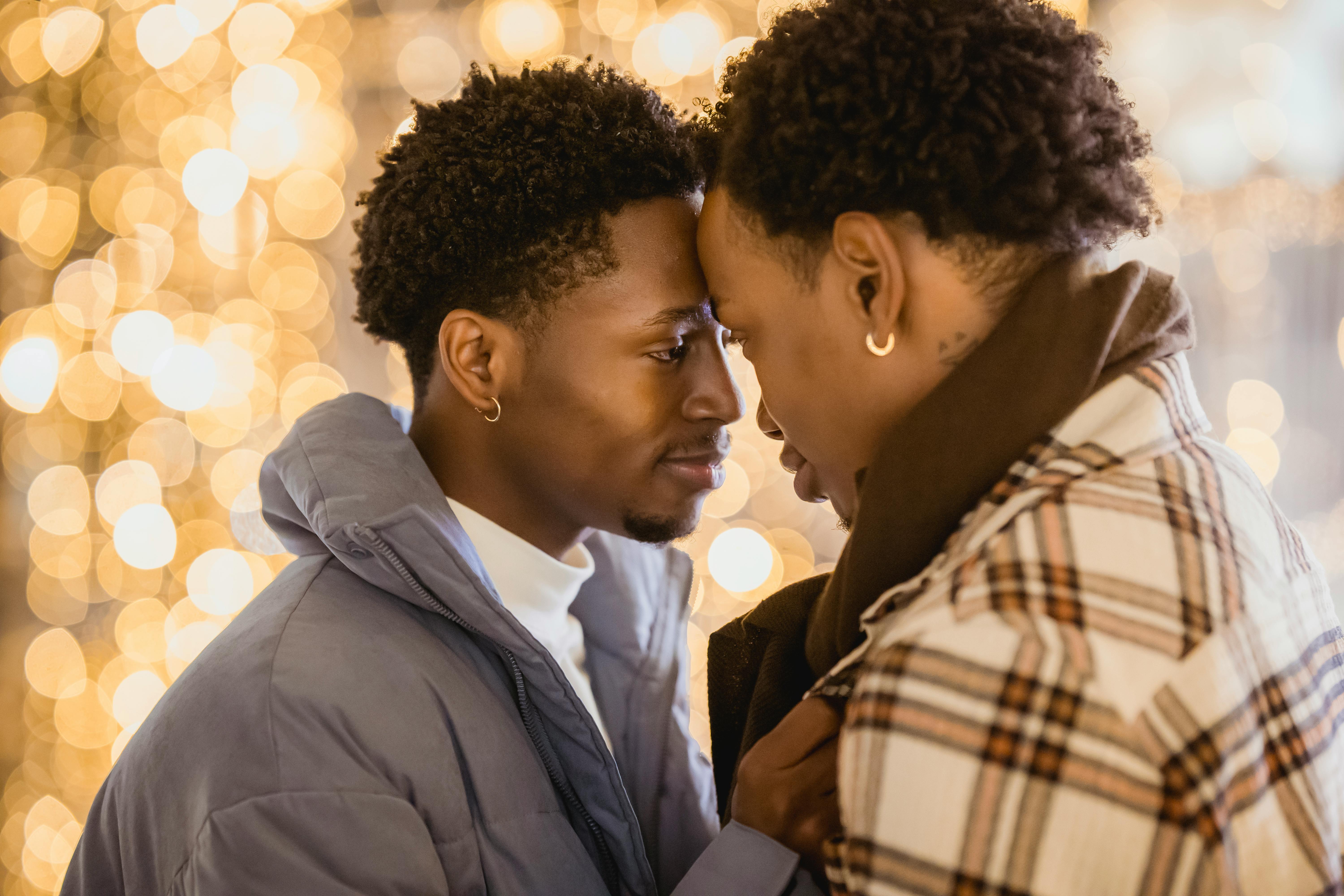 loving black couple of gays in outerwear cuddling