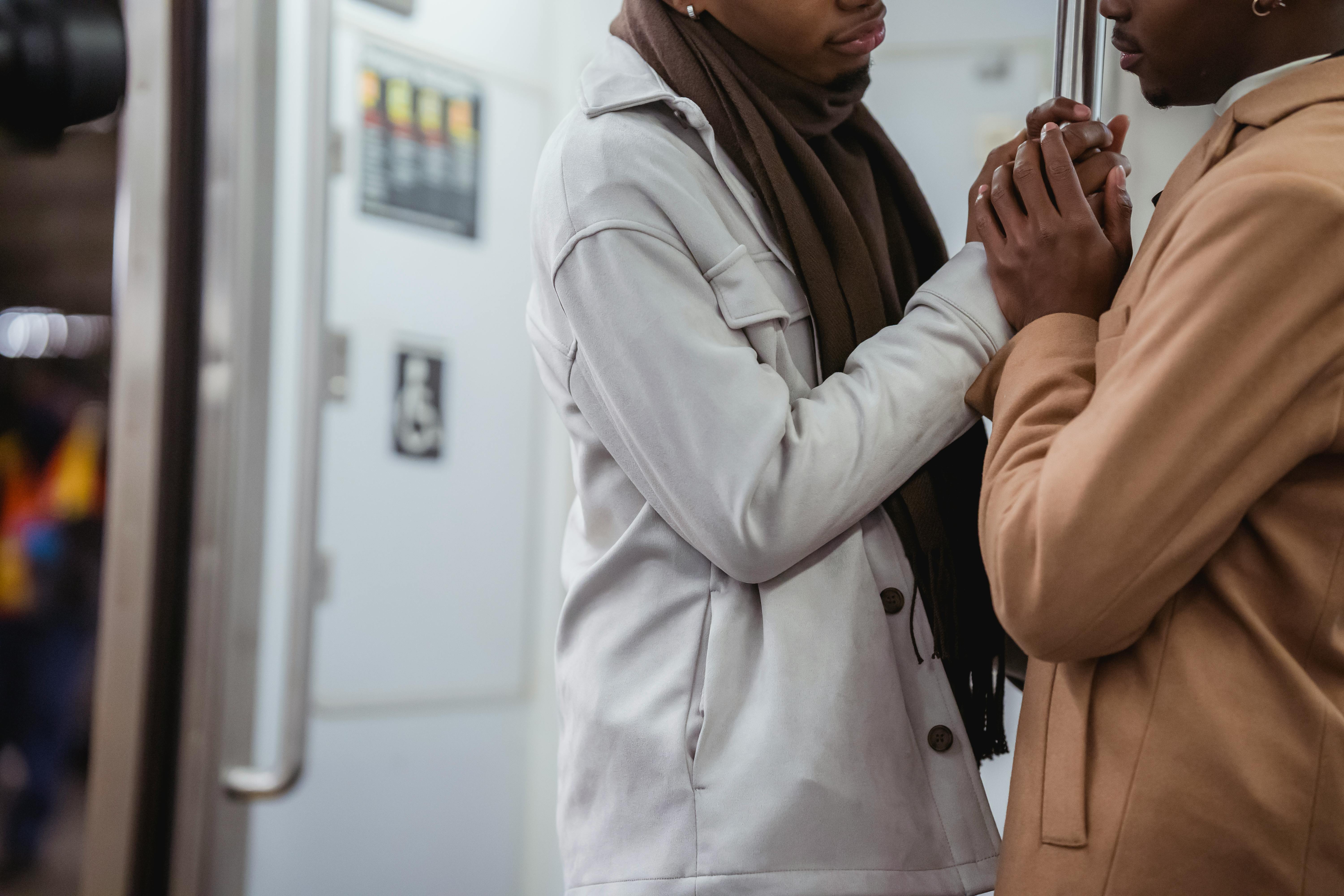 black homosexual men holding handrail in train of underground