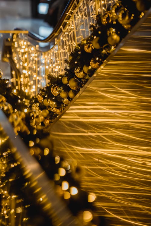 Free Shimmering golden baubles and glowing lights of garland handing on metal railing at Christmas eve Stock Photo