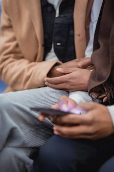Two men in stylish outfits engage with a smartphone, conveying connection and bonding.