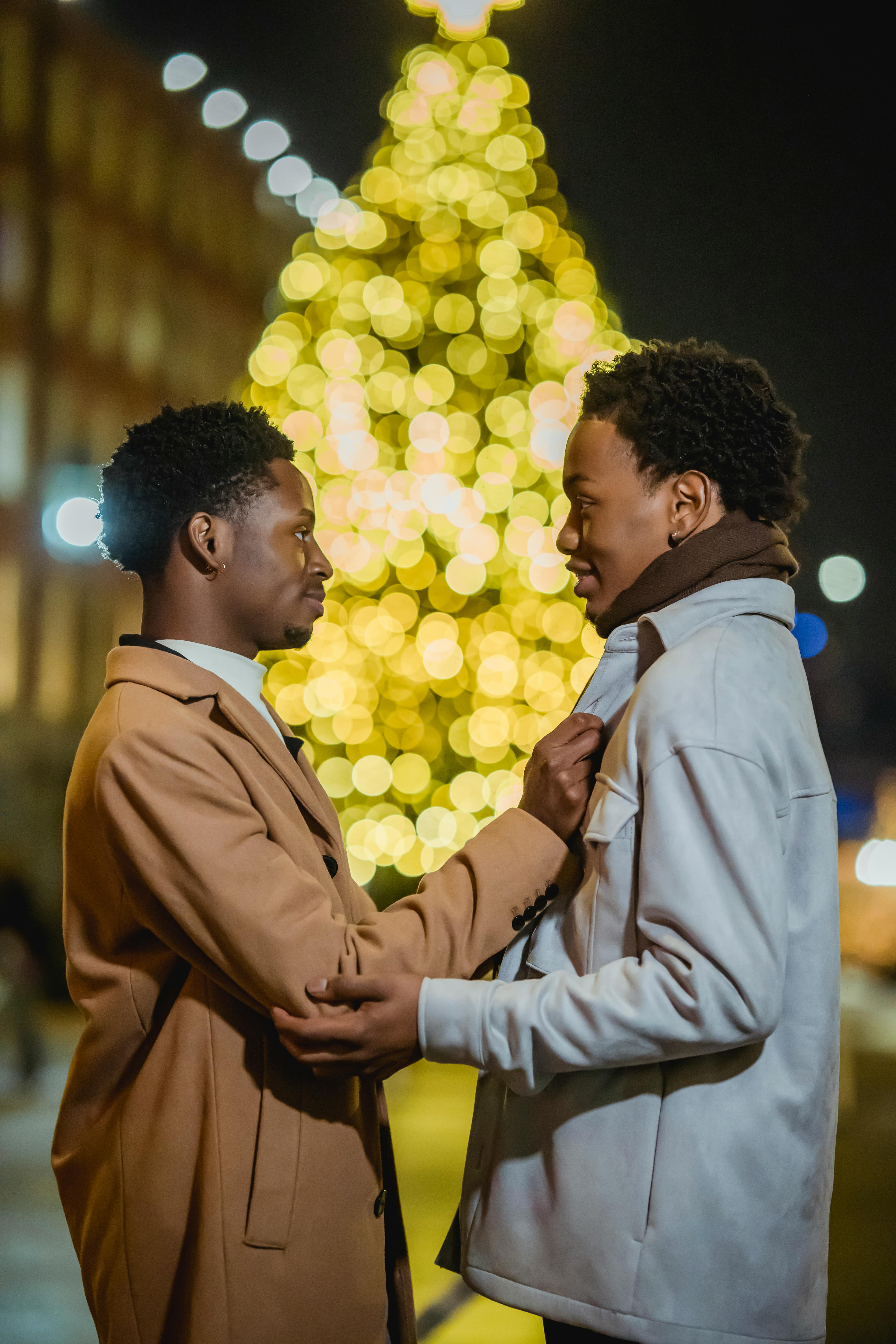 black gay couple talking against glowing christmas tree