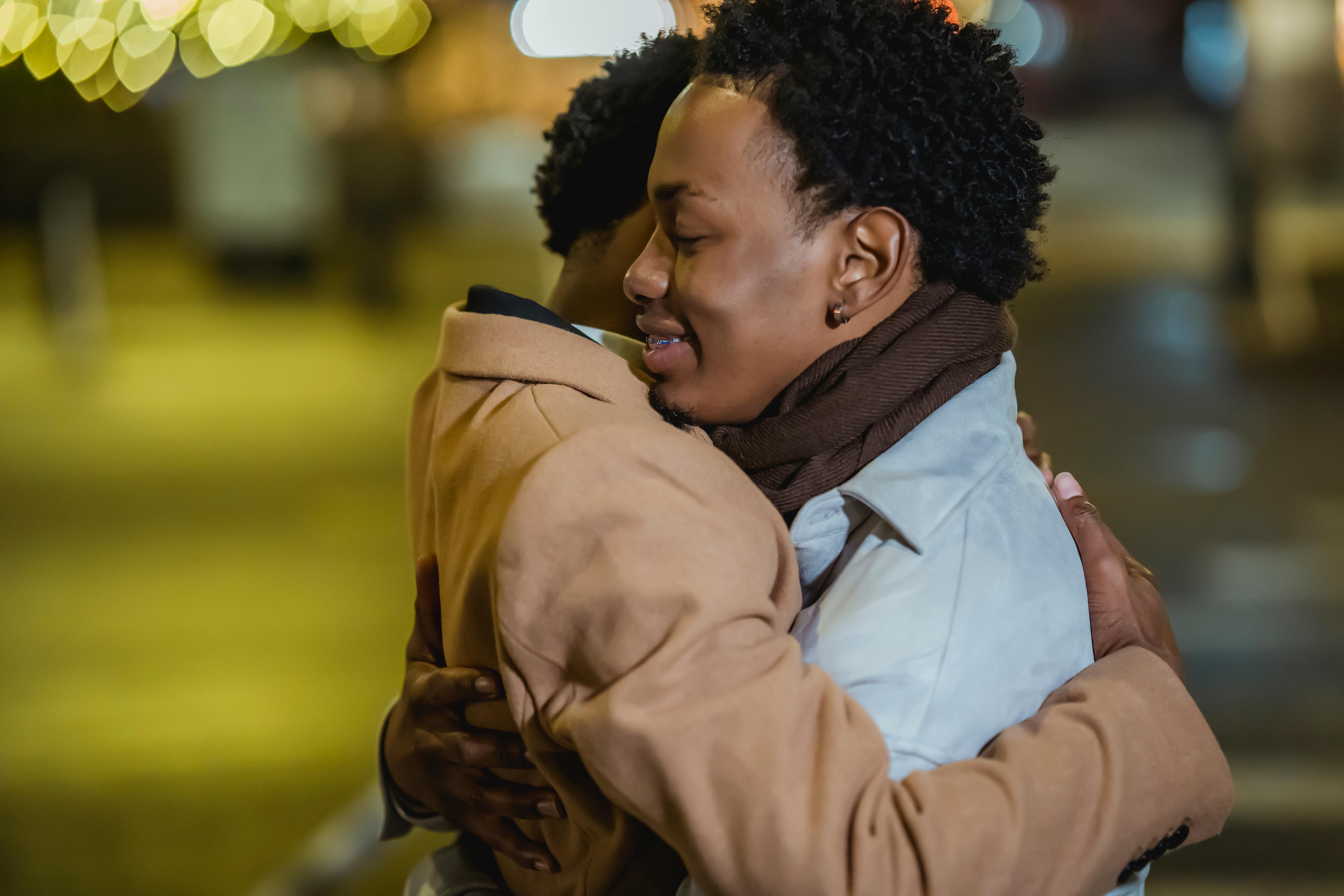 smiling black same sex couple embracing on street