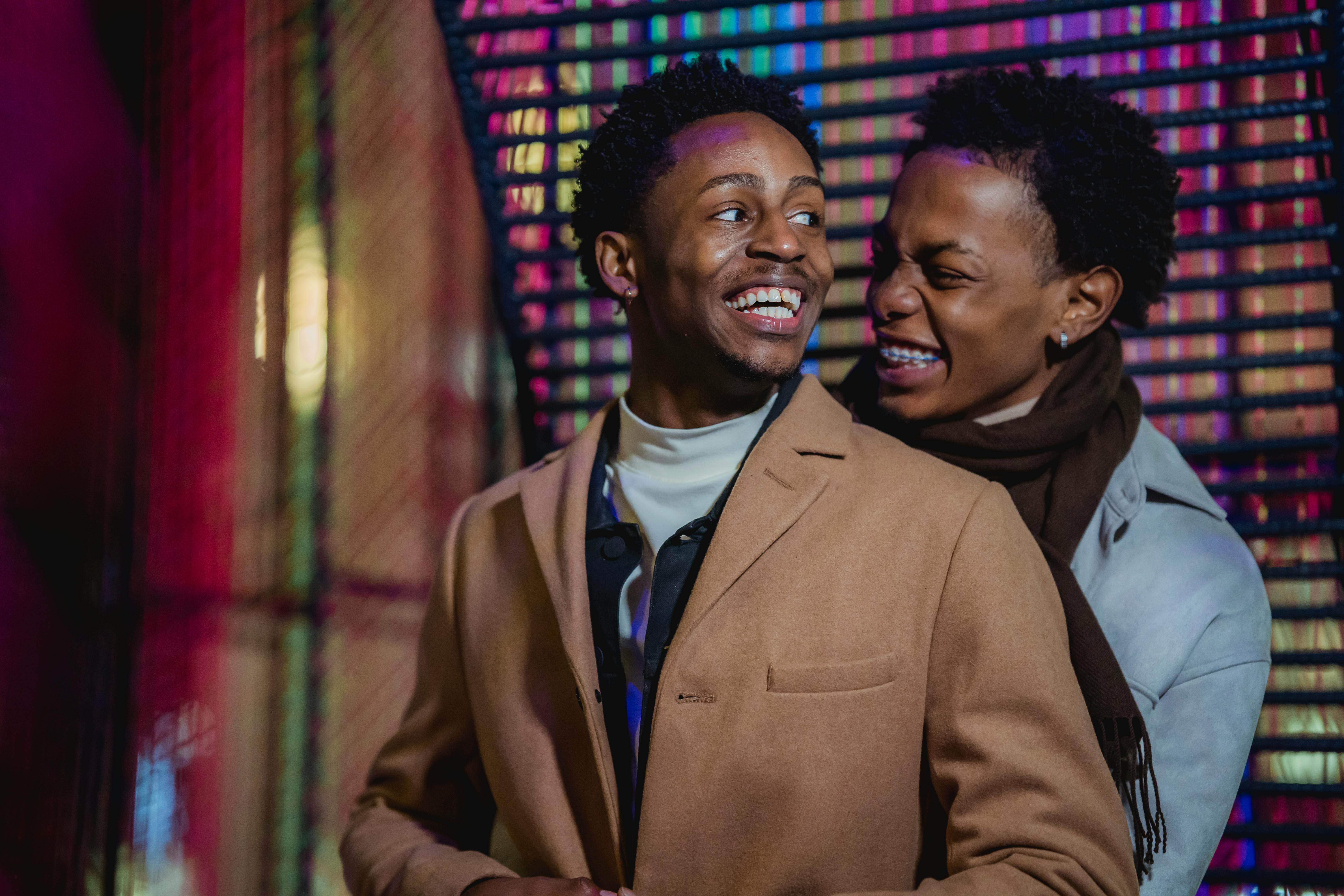 cheerful black gay couple embracing and laughing happily