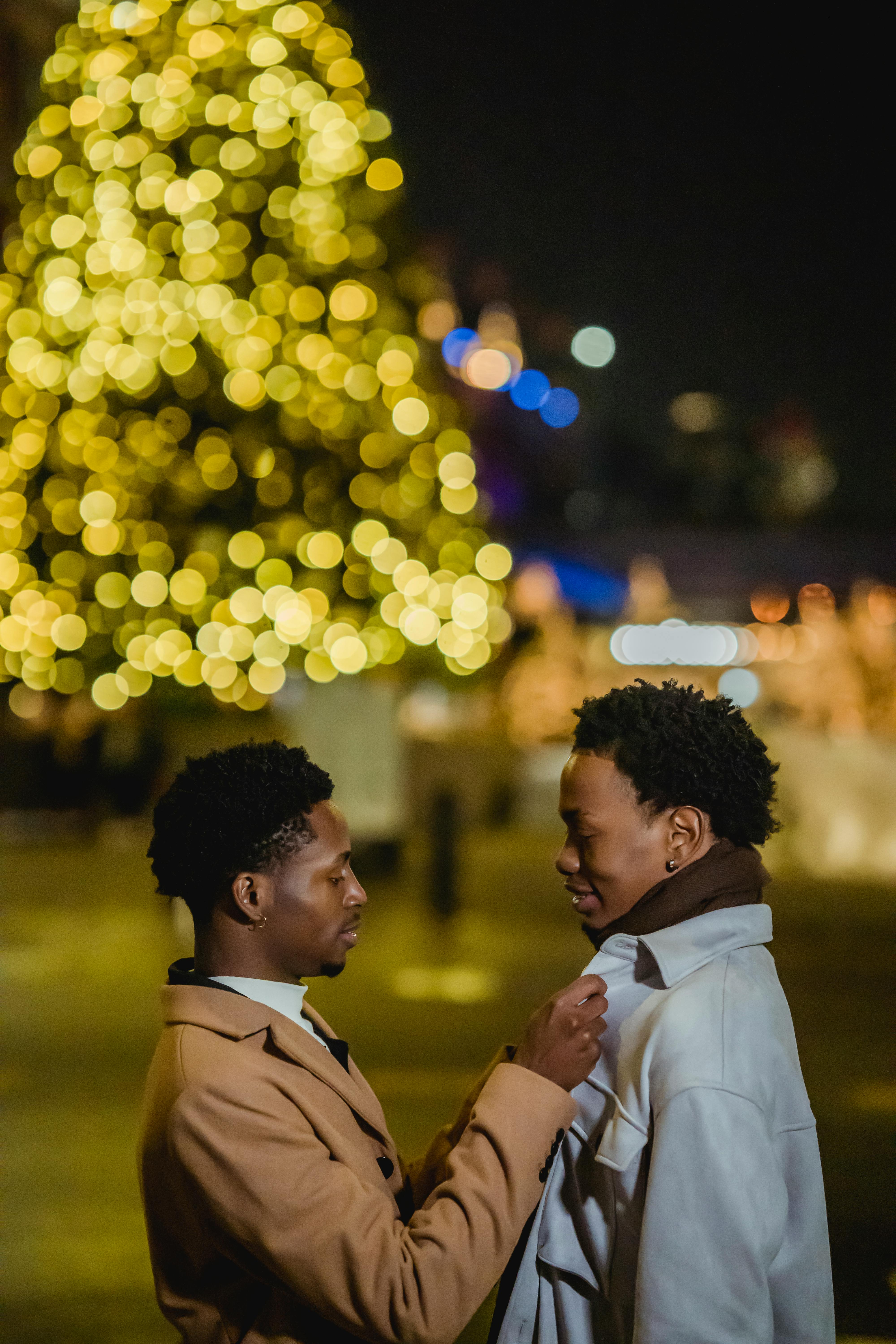 same sex couple standing on street against christmas tree