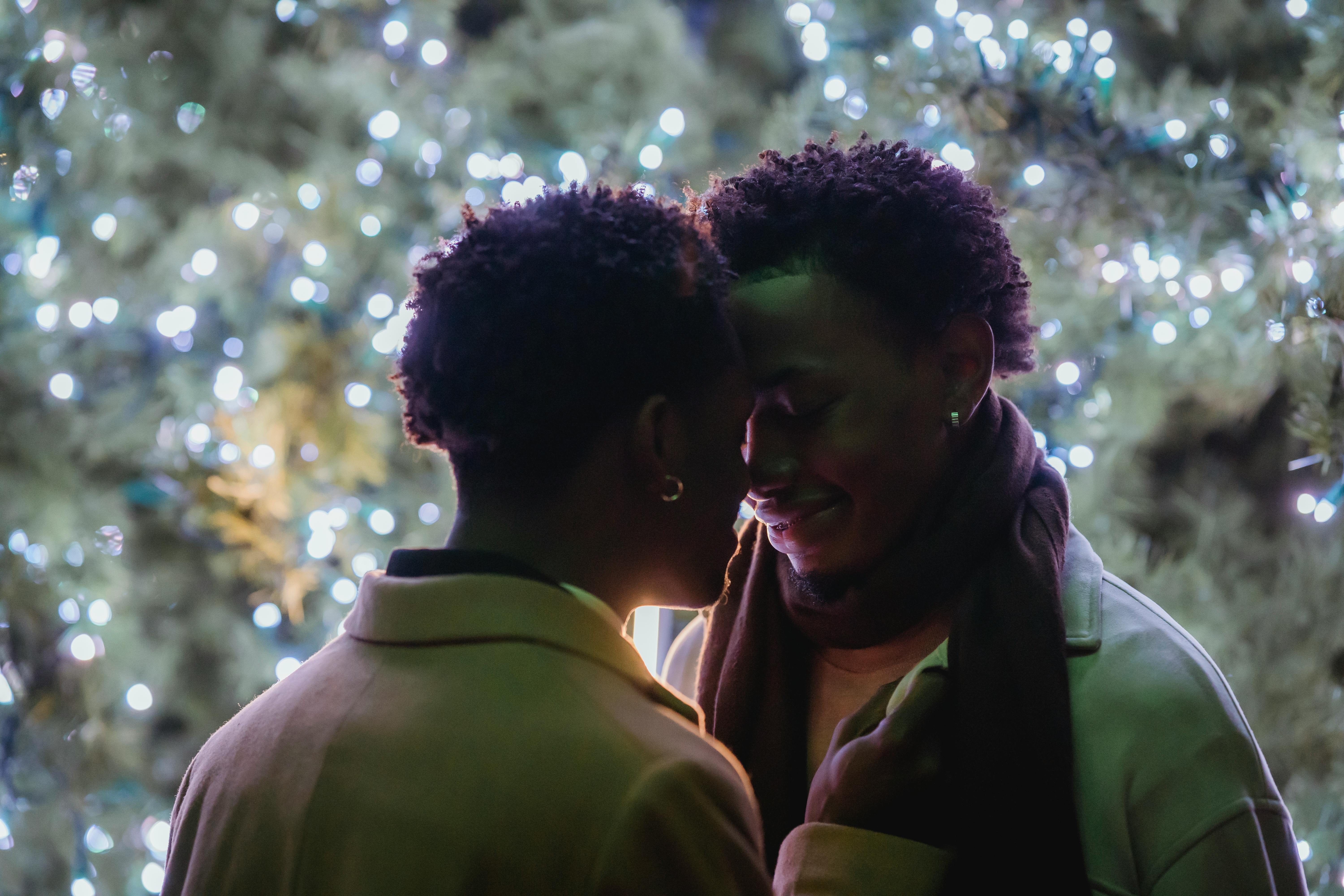 loving black homosexual couple touching foreheads against christmas tree