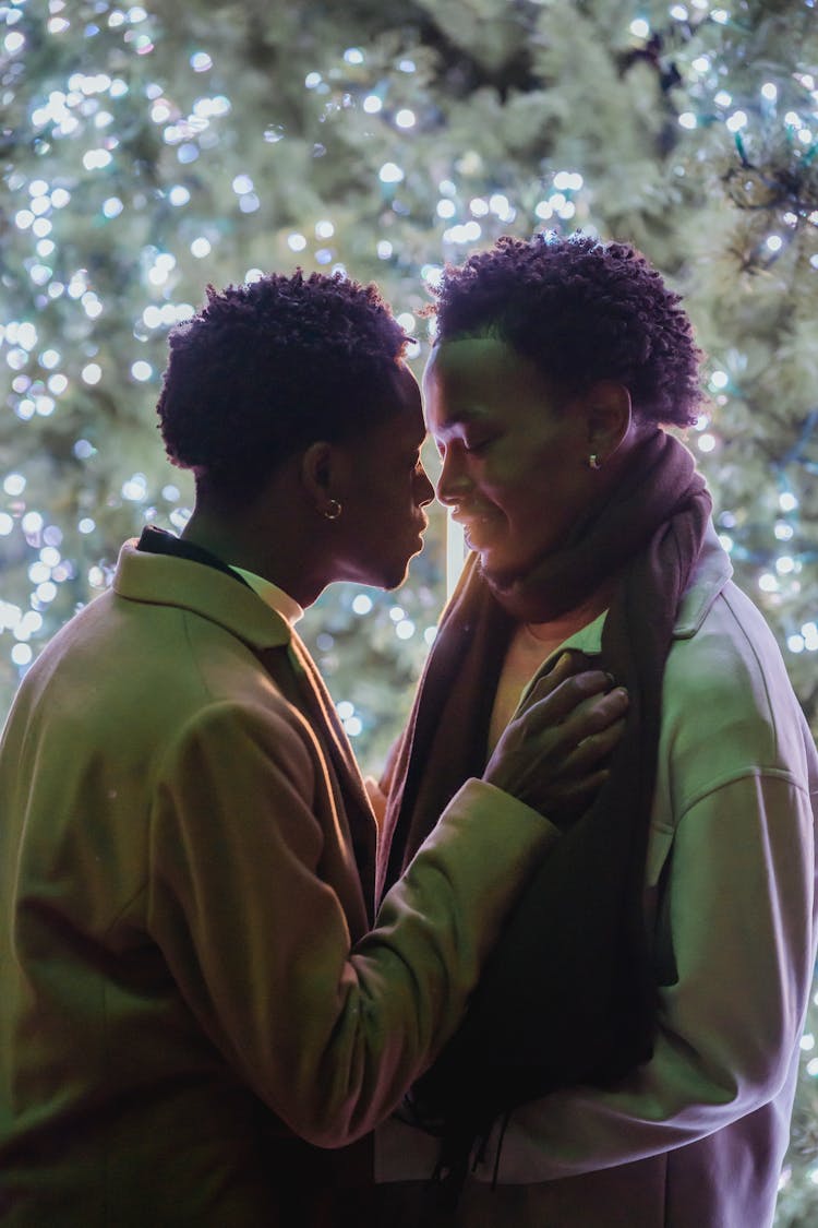 Loving Black Same Sex Couple Embracing Against Evergreen Tree