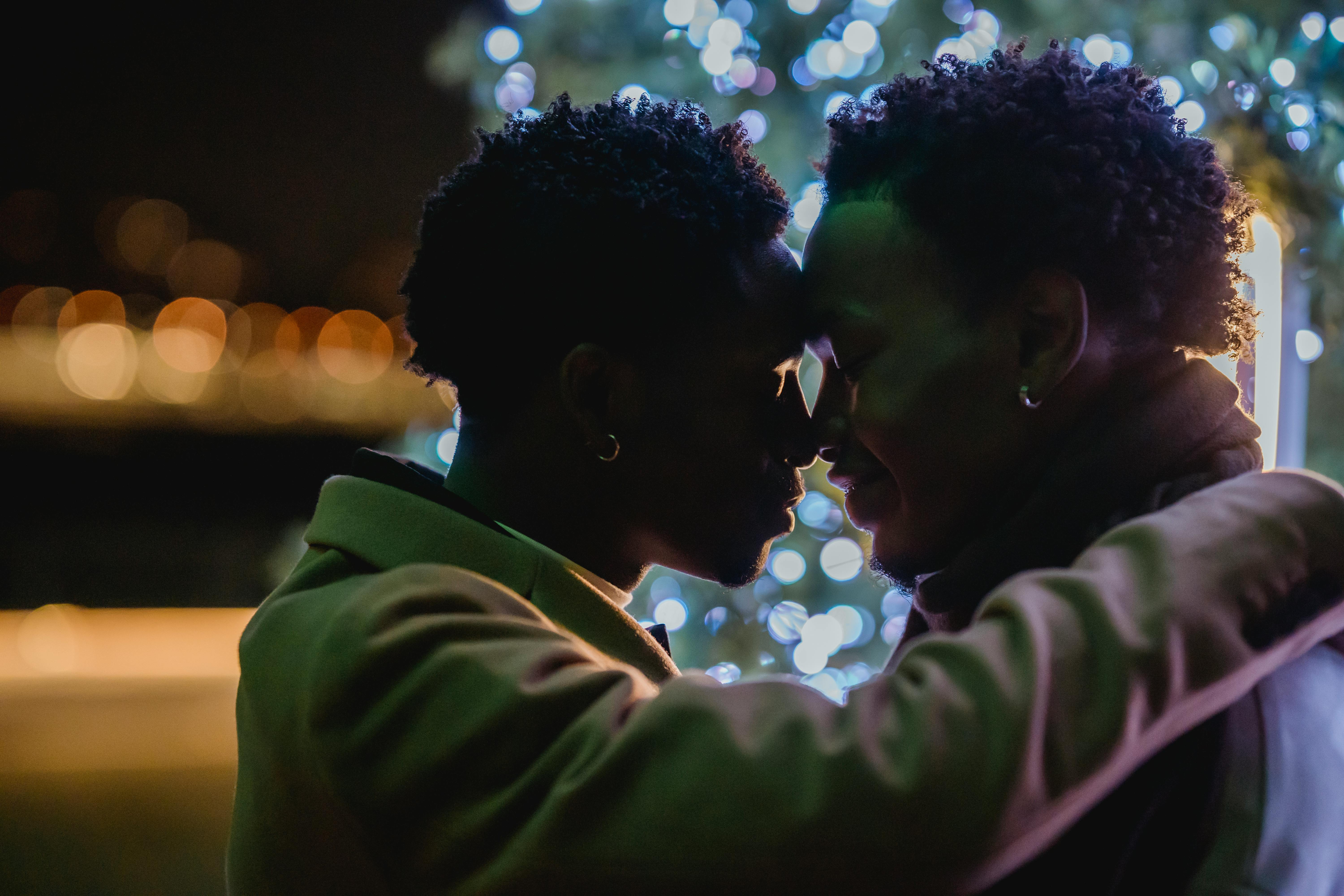 delicate black same sex couple embracing against christmas tree