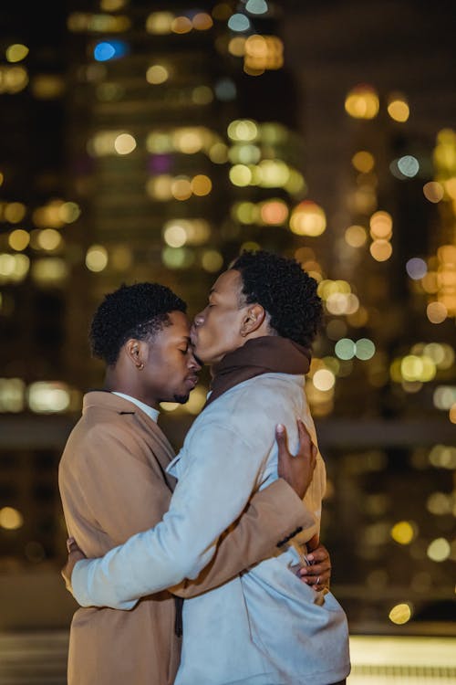 Free Black gay couple kissing and hugging in illuminating city street Stock Photo