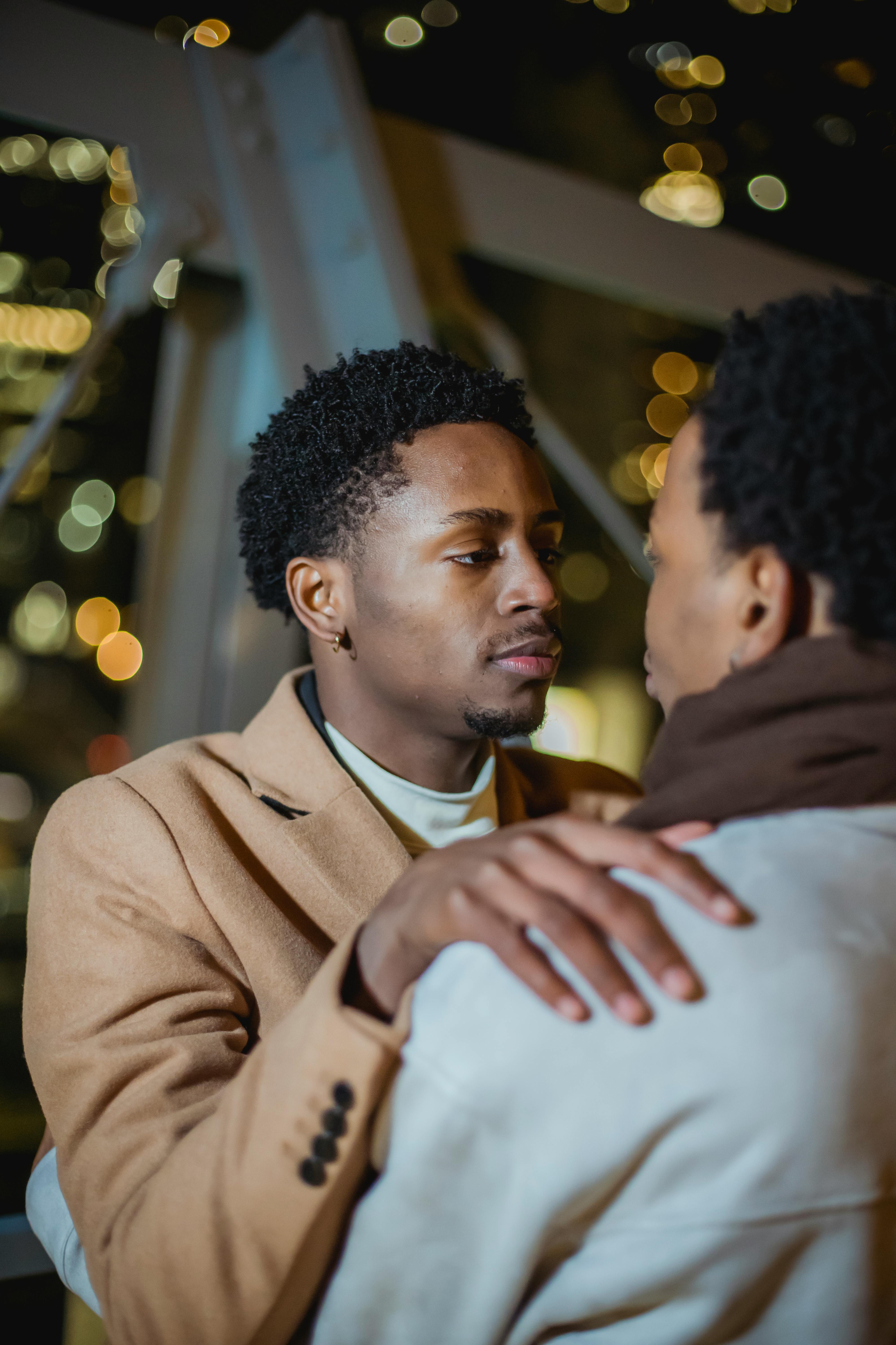 black gay couple hugging in city street against illuminating buildings