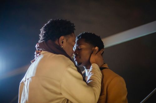 Free Young African American gay couple in outerwear hugging with closed eyes while standing nose to nose in city street at night under dark sky Stock Photo