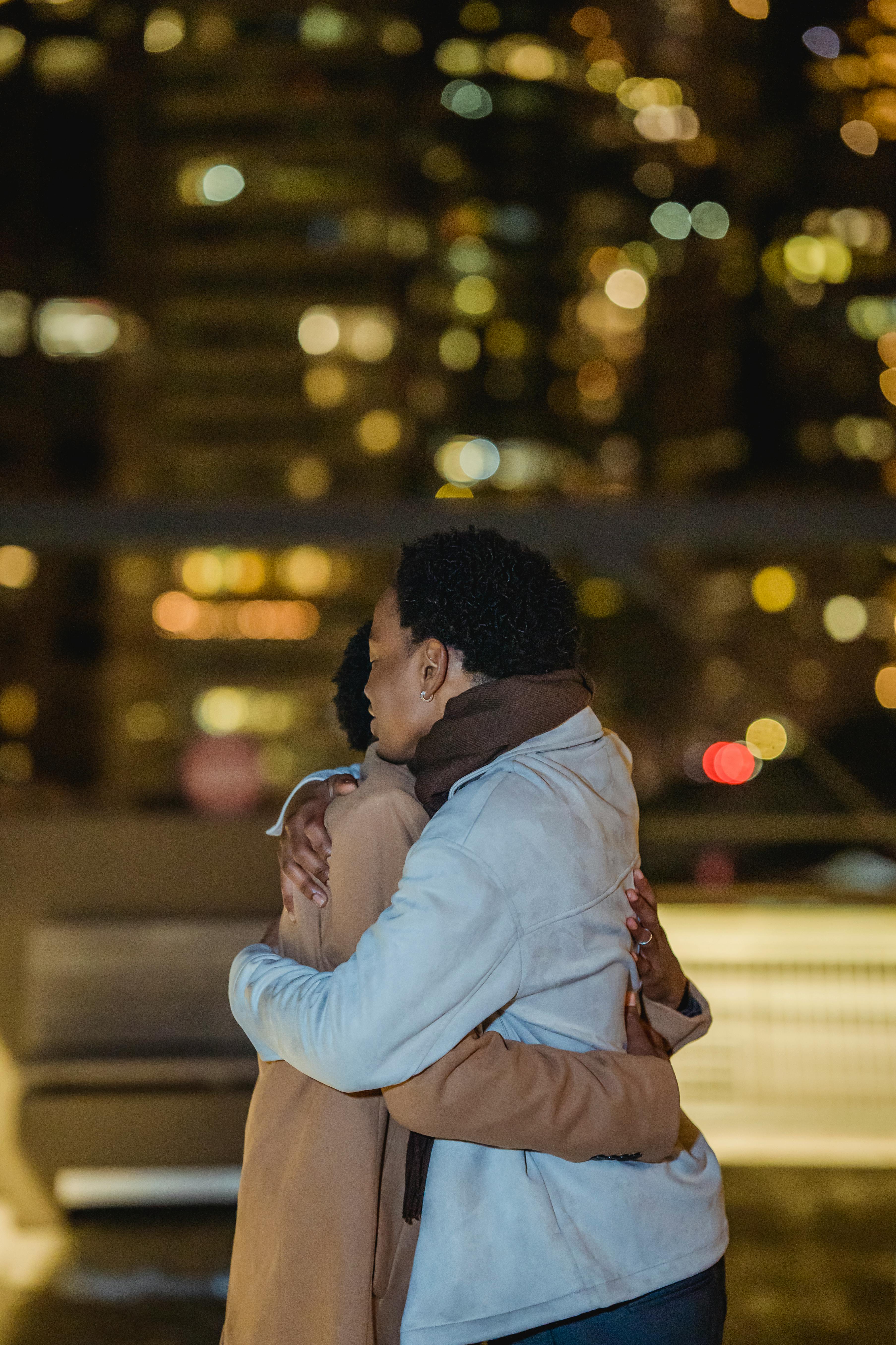 black homosexual male couple cuddling in glowing city street