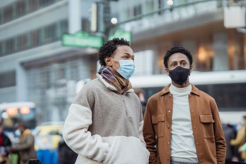 Free Serious African American couple in casual clothes wearing protective masks standing on street near building on blurred background during coronavirus pandemic Stock Photo
