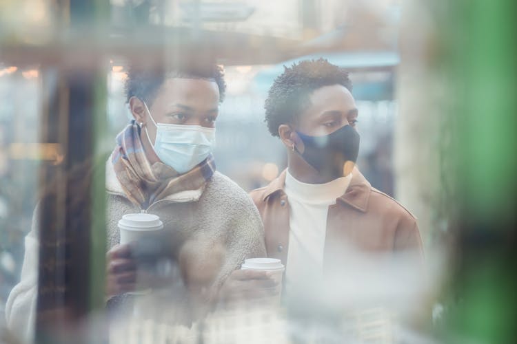 Through Glass Of Black Gays In Medical Masks Standing Near Showcase