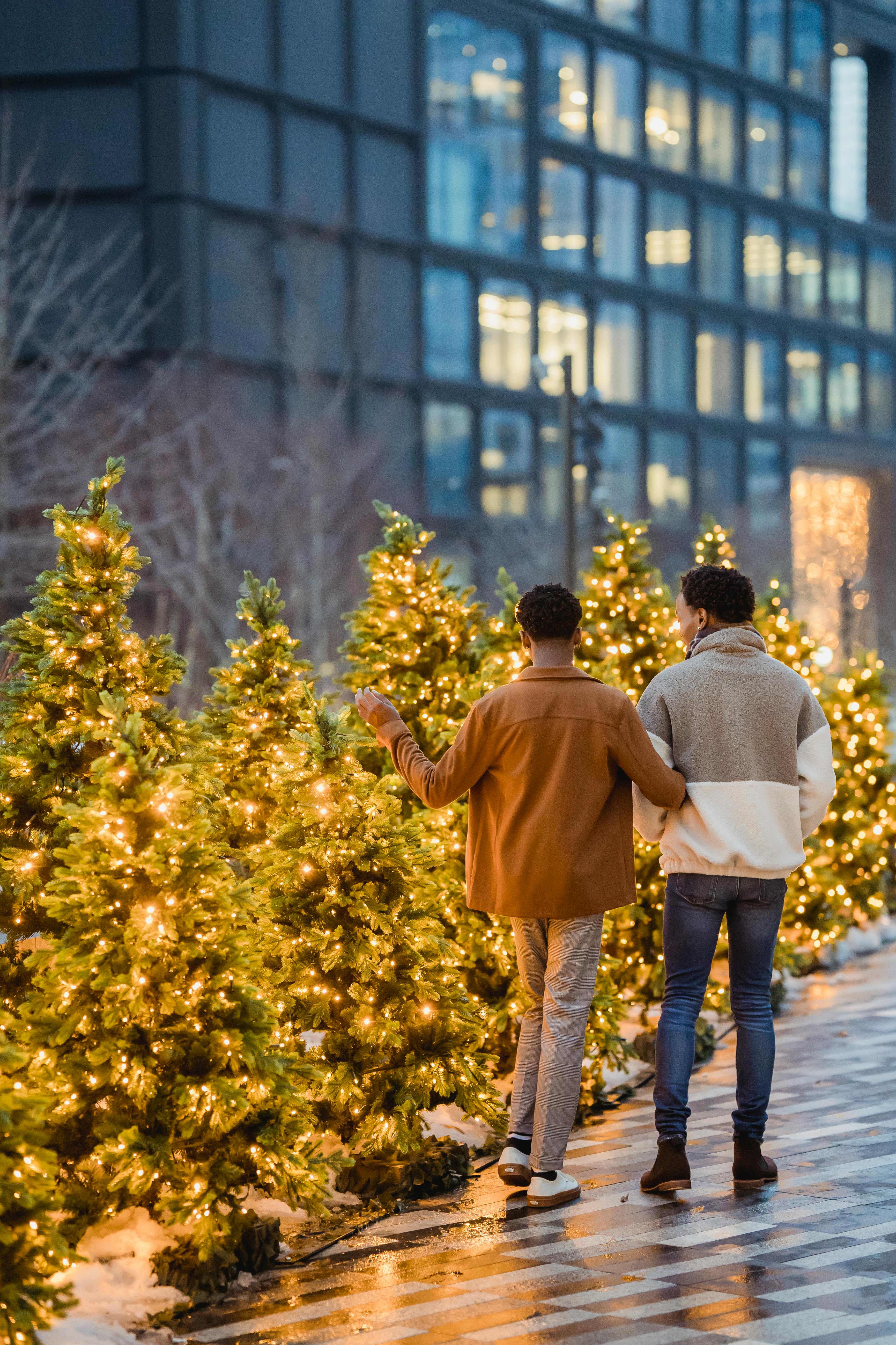 unrecognizable black gays strolling on urban walkway against fir trees