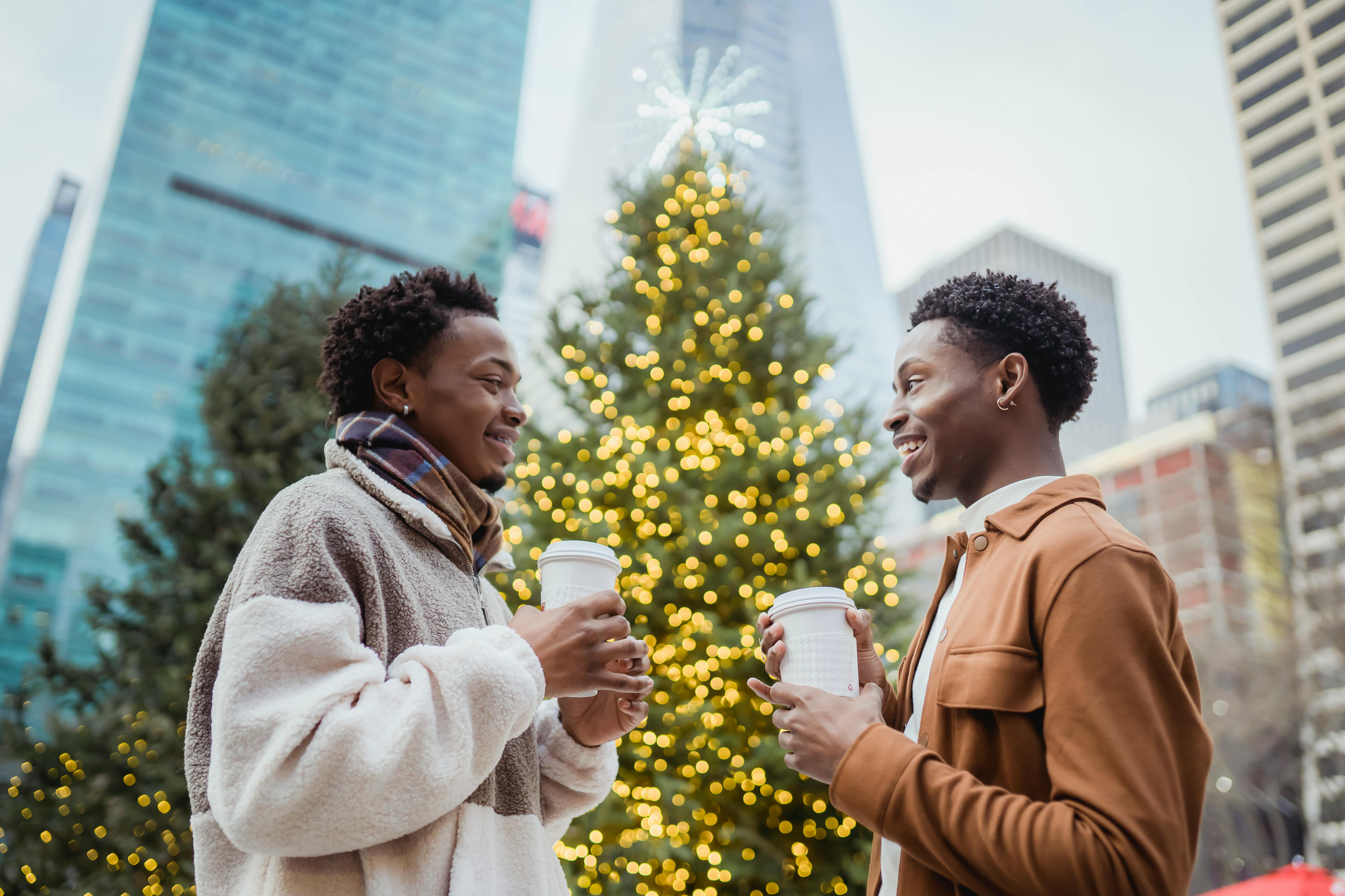 cheerful black gays with coffee to go talking in town