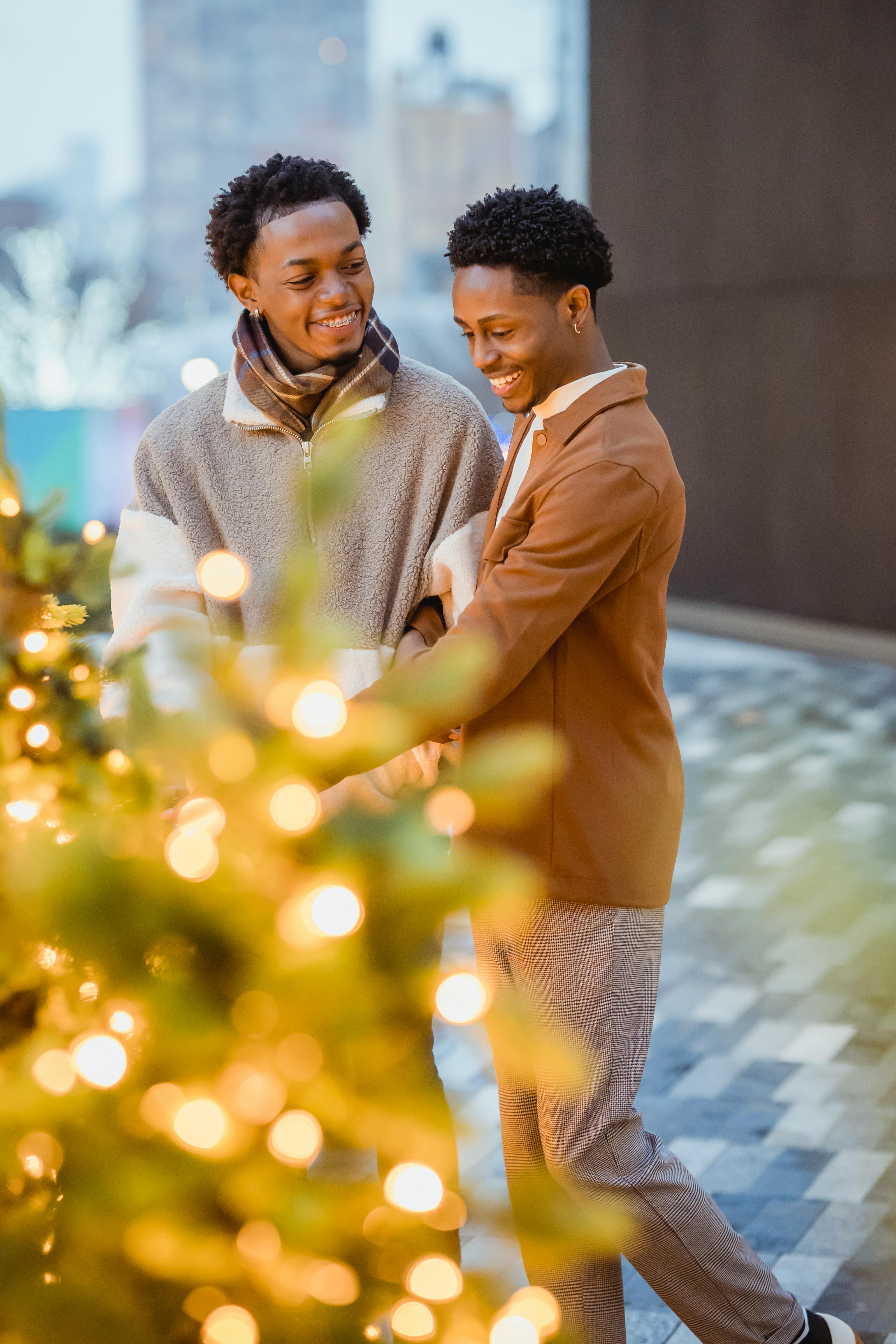 smiling homosexual black couple talking against christmas trees in town