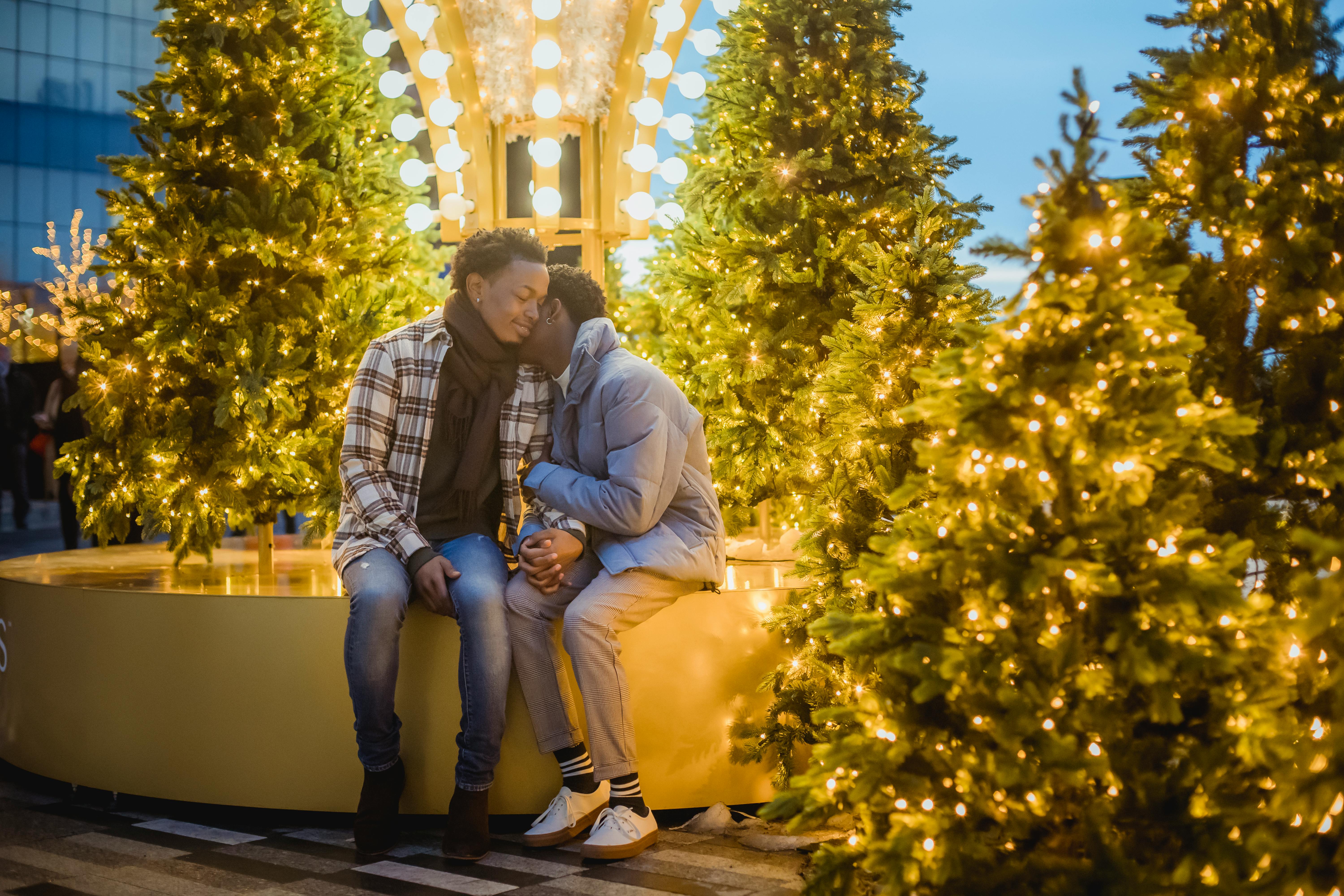 homosexual black man with unrecognizable boyfriend among christmas trees