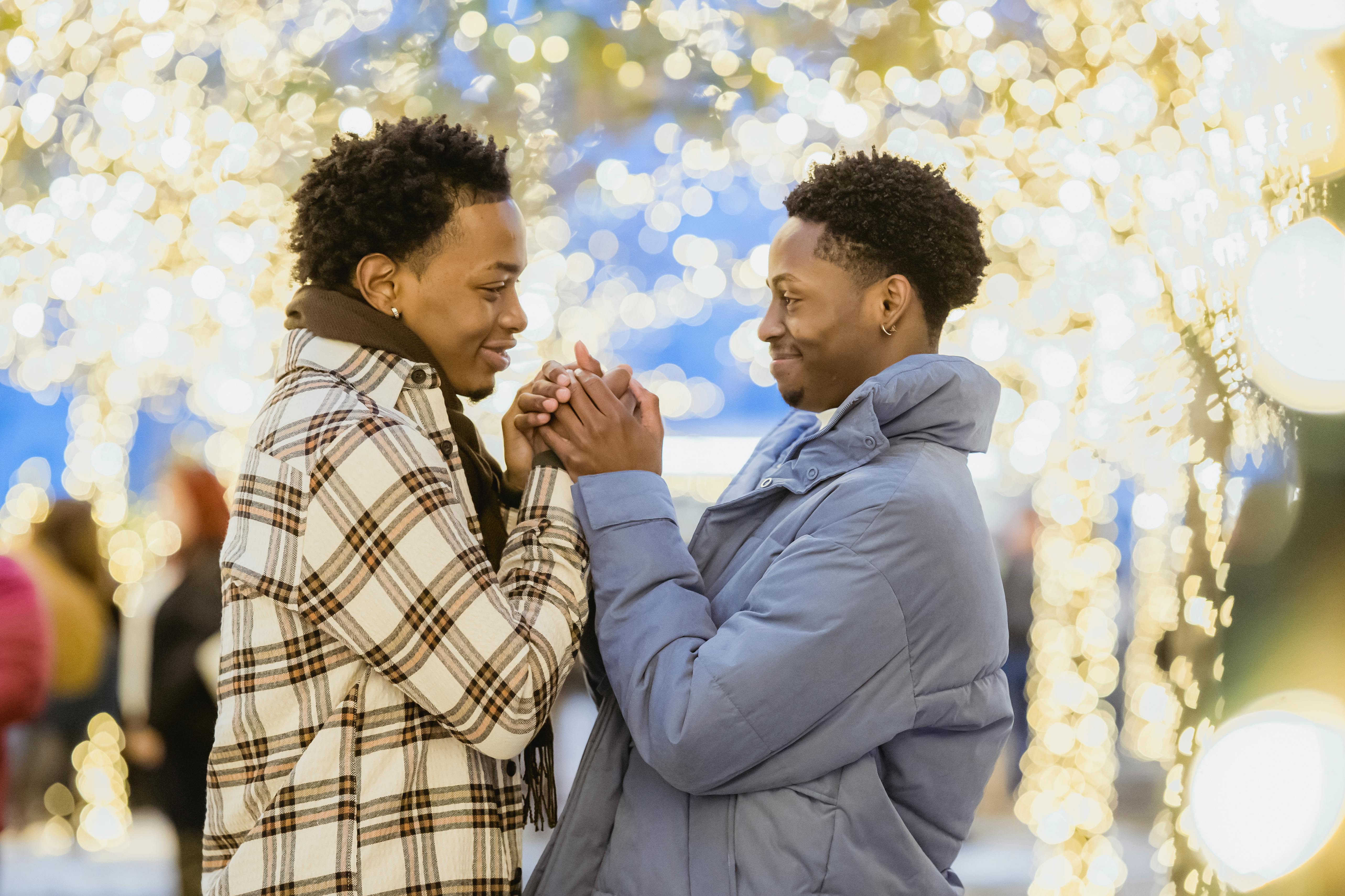 smiling black gays holding hands in town with shiny lights