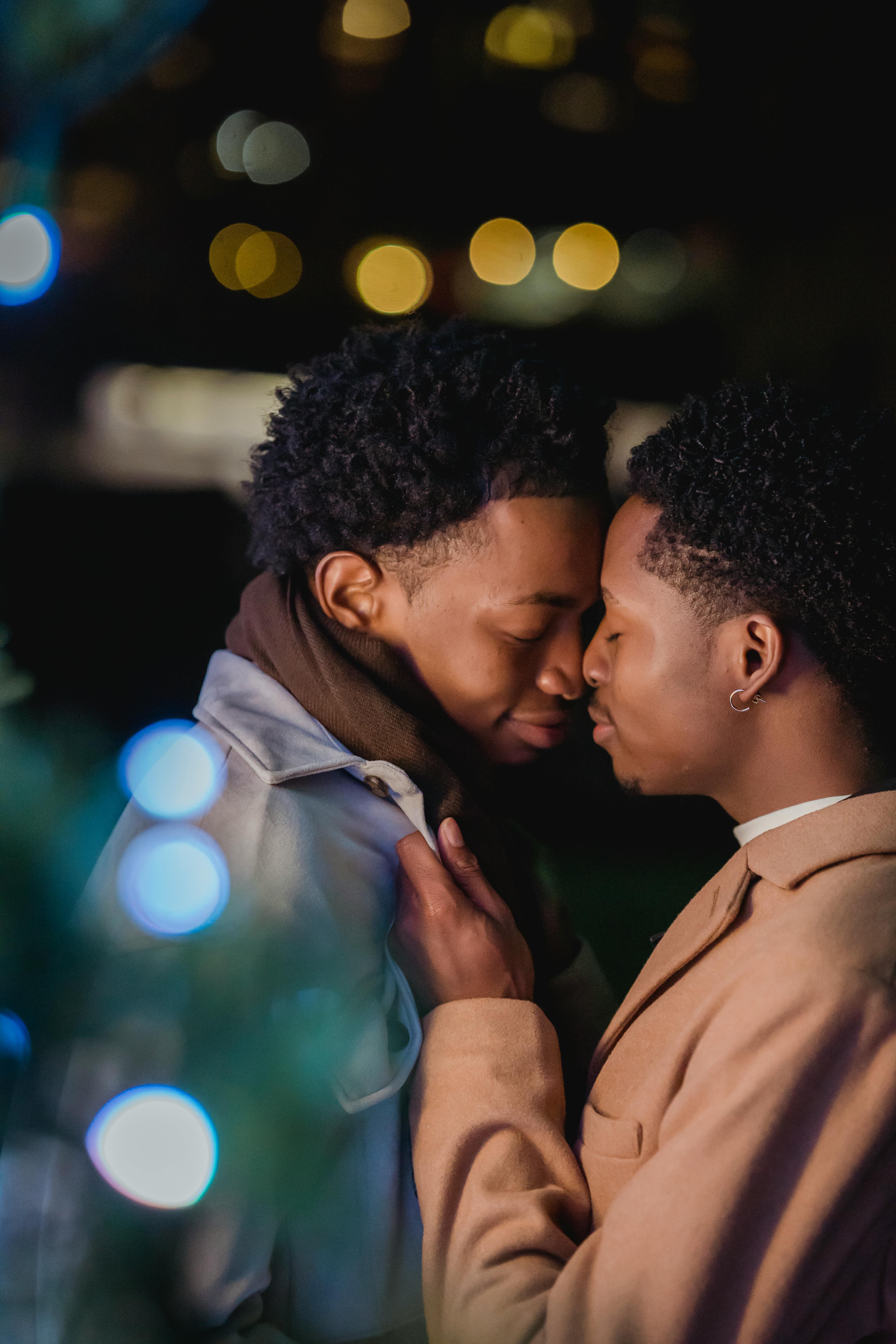 happy young black homosexual men cuddling on street at night