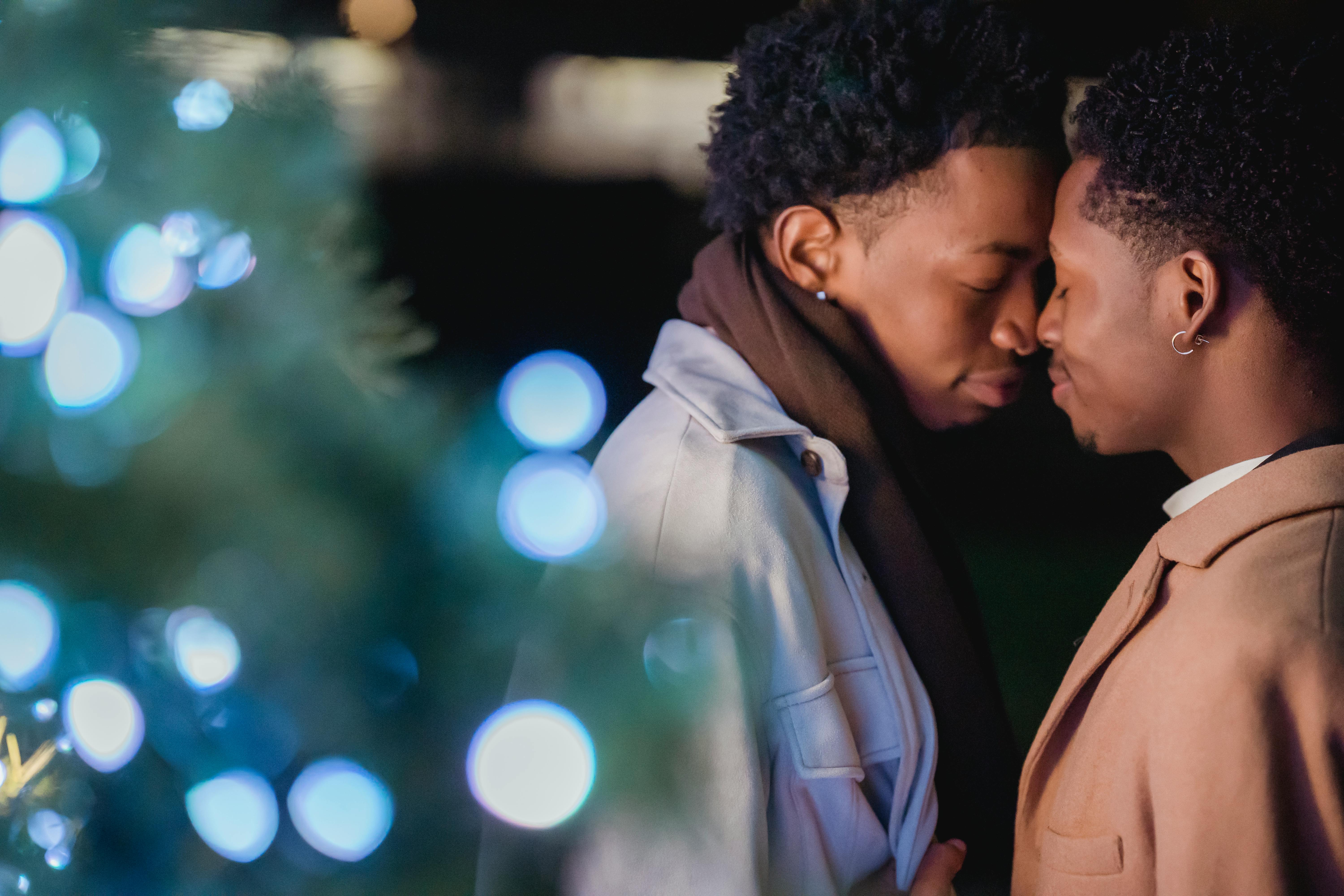 enamored young black gay couple touching foreheads with closed eyes on street at night