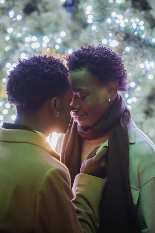 Happy young black gay couple hugging with closed eyes on street at night