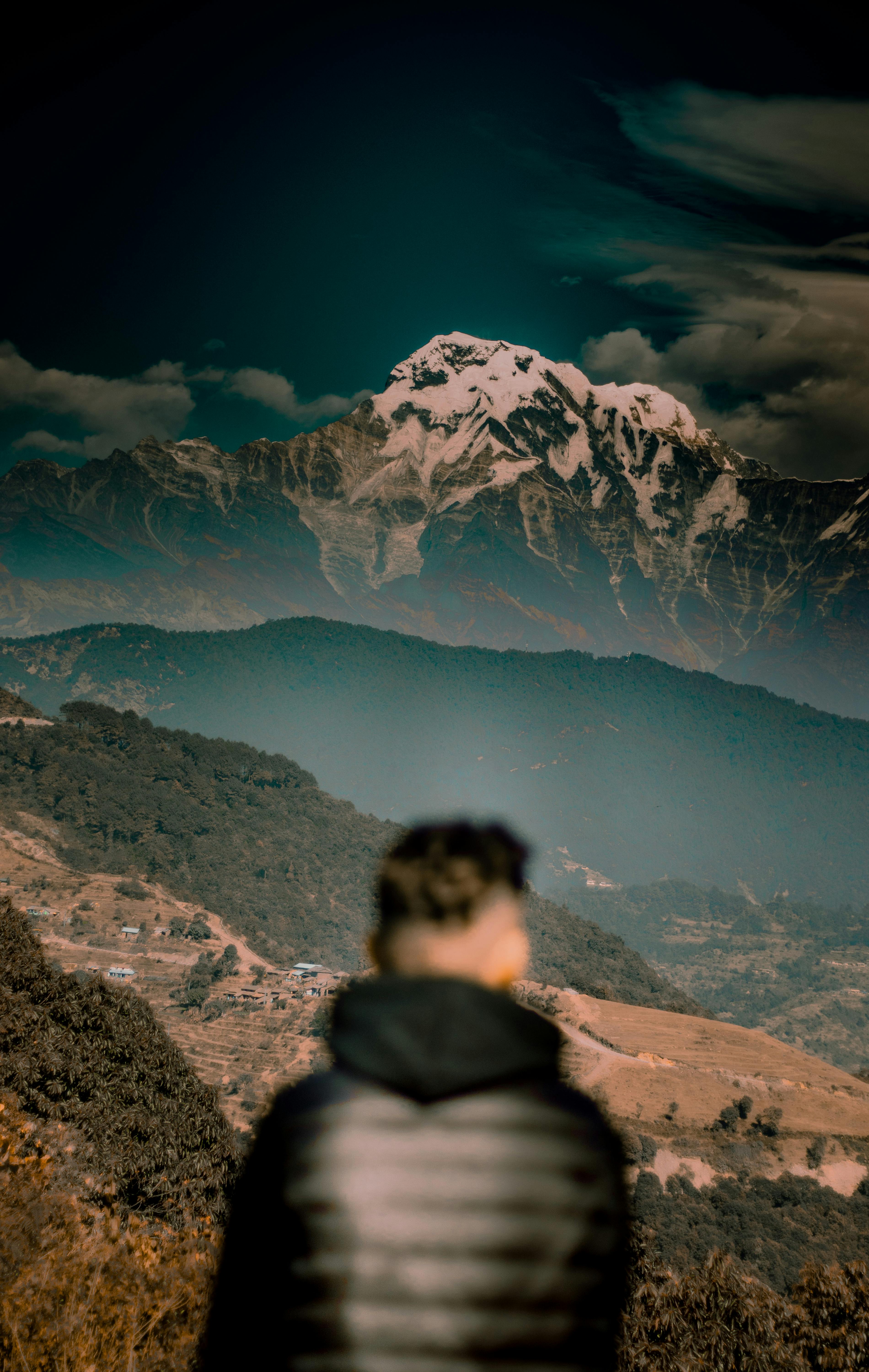 Stunning view of a snow-capped mountain with a blurred figure in the foreground, capturing nature's grandeur.