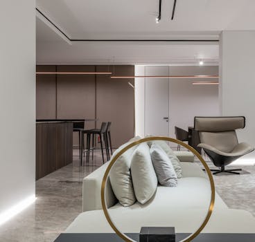 Comfortable soft couch with cushions and dining zone in kitchen in modern studio interior