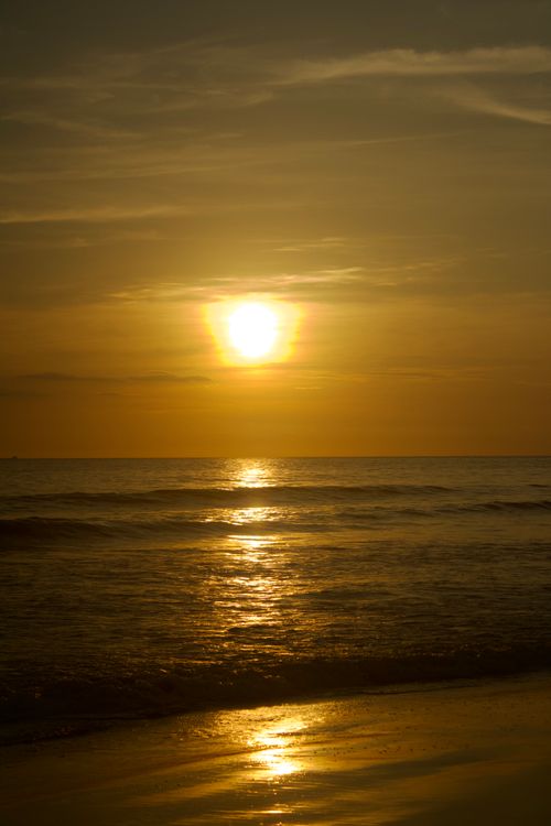 Free Tranquil seascape with the sun setting over the ocean, casting golden reflections on the water. Stock Photo