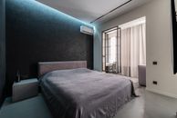 Interior design of contemporary spacious bedroom with comfortable soft bed with bedside table and air conditioner in apartment
