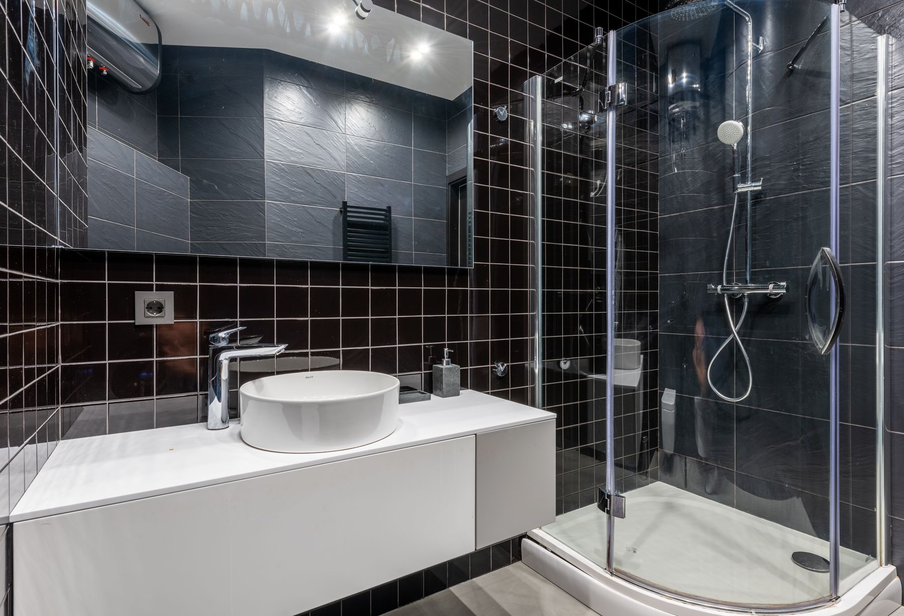 Industrial-style bathroom with black tile and strong dark surface contrast