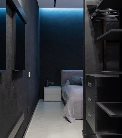 Interior of contemporary bedroom with big comfortable bed with pillows and opened wardrobe with shelves and desks