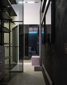 Narrow passage between opened wardrobe with wooden shelves and desks in modern stylish apartment