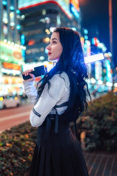 Young woman in a stylish outfit holding a glowing stick on a vibrant city street at night.