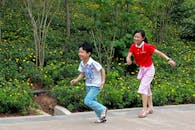 Kids Playing in the Park Near Green Plants