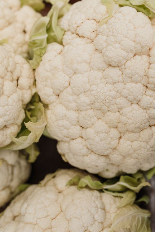 Free Vertical close-up shot of fresh organic cauliflower with green leaves. Stock Photo