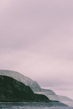 A serene view of a rugged coastal cliff under overcast skies, perfect for tranquil nature scenes.